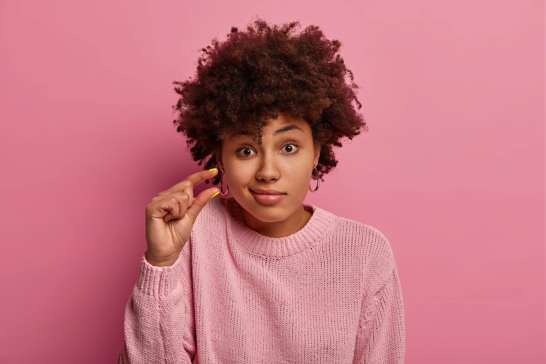 A Black woman holding her fingers to make a "small" gesture